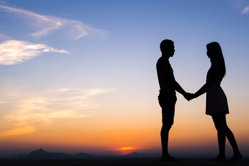 Silhouette of Happy Young Couple Hugging Outside at Sunset,proposing