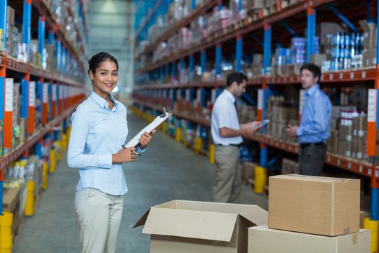 Portrait of female warehouse worker standing with clipboard