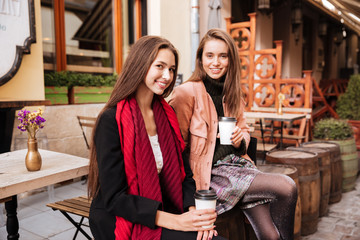 Two happy women sitting and drinking coffee in old city