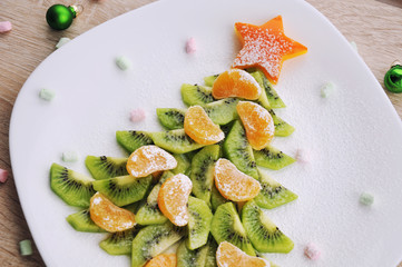 Christmas healthy dessert idea for party - funny edible kiwi tangerine Christmas tree.