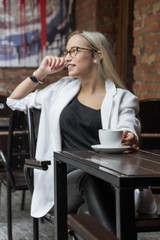 young business woman blonde in glasses in cafe