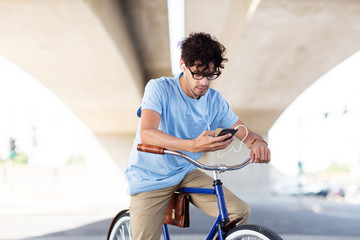 man with smartphone and earphones on bicycle