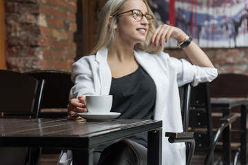 young business woman blonde in glasses in cafe
