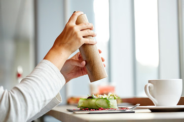 woman with salt shaker and salad at restaurant