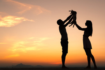 Silhouette of Happy Young Couple playing with cat Outside at Sunset