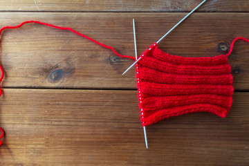 hand-knitted item with knitting needles on wood