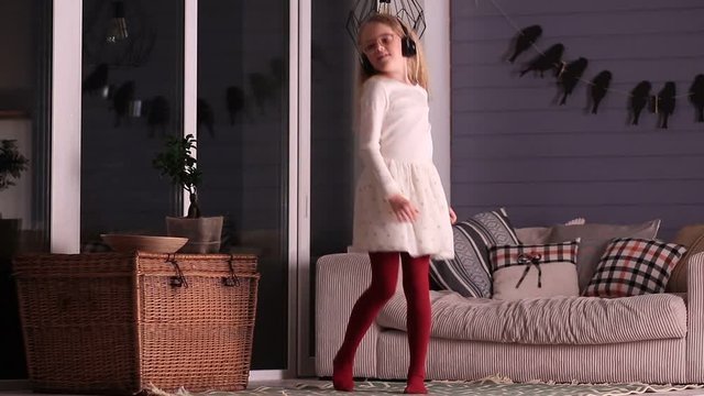 Dancing little girl with headphones at home