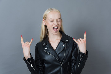 crazy blond girl in a leather jacket giving the Rock and Roll Si