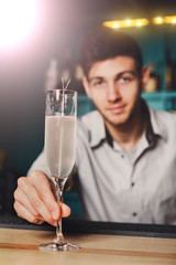 Young Barman offers champagne glass in night club bar