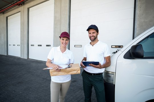 Delivery man and woman standing with clipboard 