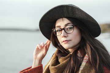 close portrait of a girl with glasses and hat at the lake