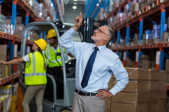 Warehouse manager pointing upwards