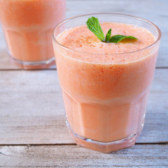 Close up of a glass of papaya smoothies on a wooden table.