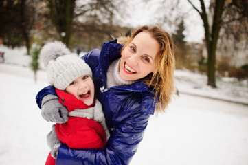 Fototapeta na wymiar Mother with daughter against background of snow-covered city yard.