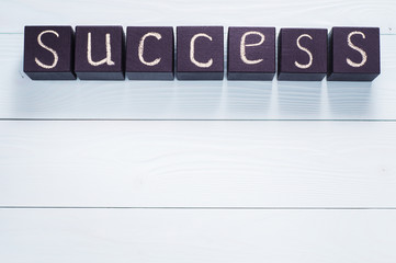 The word success written on a black wooden cubes, flat lay.