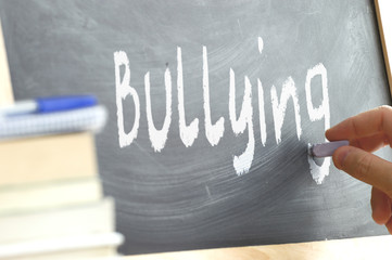 The word Bullying hand written on a blackboard. Adolescence problems at the stages or schooling.