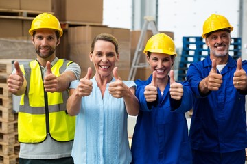 Portrait of warehouse manager and worker showing thumbs up - Powered by Adobe