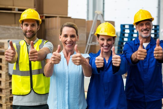 Portrait of warehouse manager and worker showing thumbs up