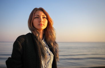 Outdoors portrait of young beautiful girl in autumn near the sea