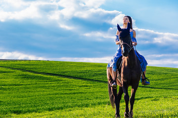 beautiful young woman riding a horse in a meadow
