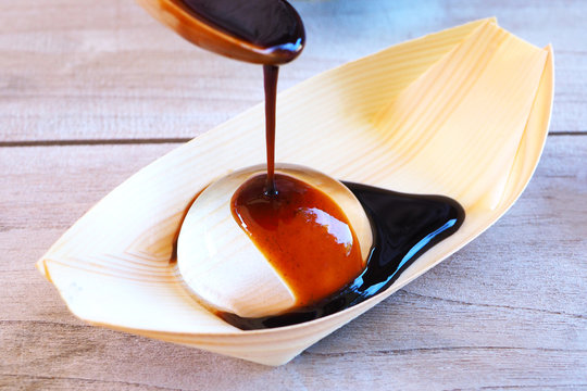 Close up of syrup on a Japanese water drop cake on a wooden table.