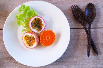 Top view of sliced orange and passion fruit on a white plate. healthy concept.