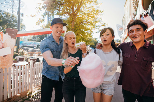 Friends eating cotton candy in amusement park