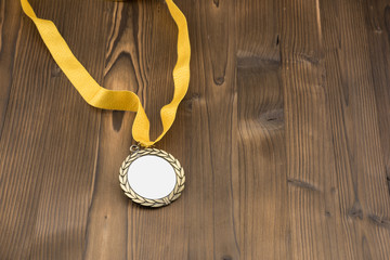 Gold medal with white placeholder and yellow ribbon on wooden textured table