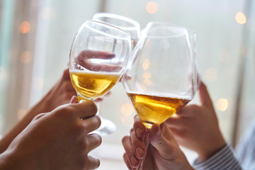 Clinking glasses of champagne in hands on bright lights background
