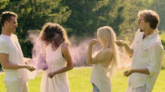 Excited friends playfully fighting with colorful powder, having fun at party