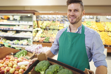Young seller holding box of broccoli