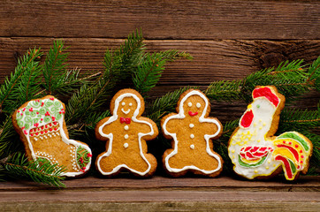 Gingerbread: sock, rooster, gingerbread men. Fur-tree branch against the background of a wooden wall with space for text