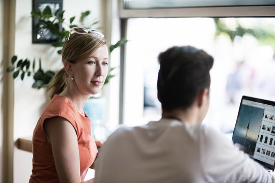 Woman looking at teenage boy using laptop