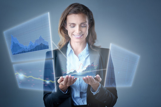 Smiling business woman analysing financial graphs on multiple vi