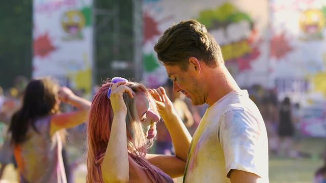Seductive young female dancing to boyfriend, couple covered in holi colors