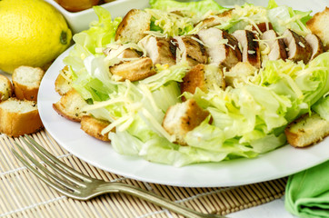 Fresh healthy Caesar Salad with grilled breast chicken and cheese placed with lemon and croutons.Close up view.Healthy diet food concept.