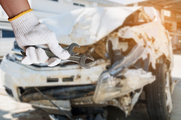 hand hold wrench with car crash damage background