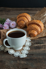 Breakfast. Coffee and croissants. Dark wood background. Vertical