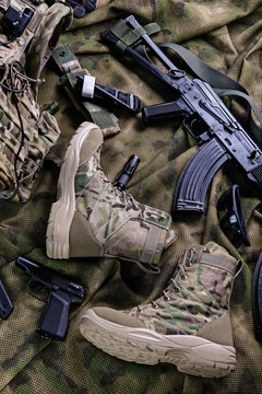 Pair of modern military footwear/Pair of modern military boots, rifle,pistol and glasses.Top view.Selective focus