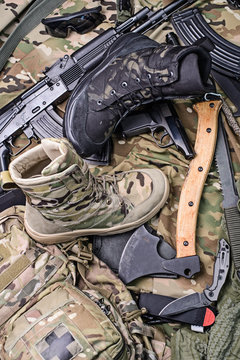 Different modern combat boots/Various army boots, ax, gun, knife, sunglasses and ammo.Top view.Selective focus