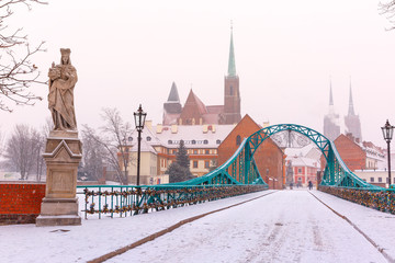 Naklejka premium Tumski Bridge and Island with Cathedral of St. John and church of the Holy Cross and St. Bartholomew in the snowy overcast winter day in Wroclaw, Poland