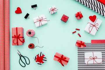Gift boxes wrapped in red checked paper and the contents of a workspace composed. Different objects on a mint color table. Flat lay.Christmas (xmas) or New year gift packing. Holiday decor concept.