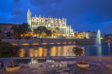 Illuminated Cathedral of Palma de Mallorca seen from Parc de Mar after a heavy rain shower