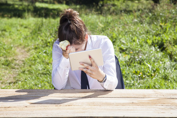 Fototapeta premium depressed business woman eating an apple and reading messages