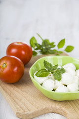 Mozzarella in a green plate on a wooden table. Mozzarella balls