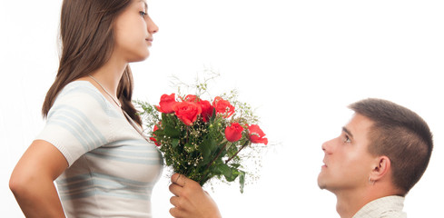 Young man kneeling and giving bouquet of roses to his girlfriend