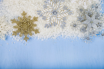 Fototapeta na wymiar Silver decorative snowflakes and snow on a blue wooden backgroun