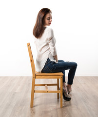 Young pretty model woman posing in studio on chair