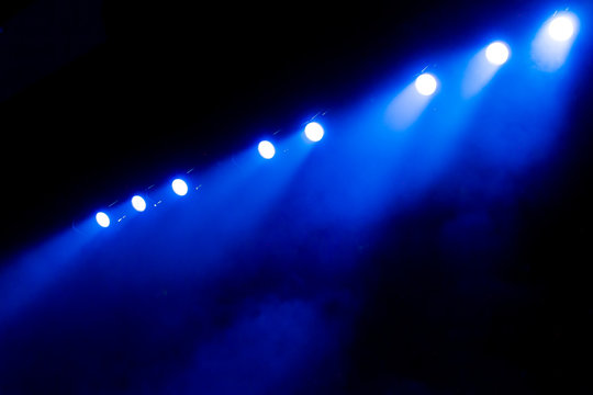 Blue light of searchlights in smoke on stage. Theatrical performance or show