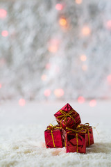 Four red gift boxes on the background of bokeh and snow. Selective focus